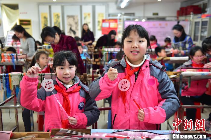 圖為小學(xué)生展示繡制好的2022年北京冬奧會(huì)吉祥物“冰墩墩”形象。　喻云亮 攝