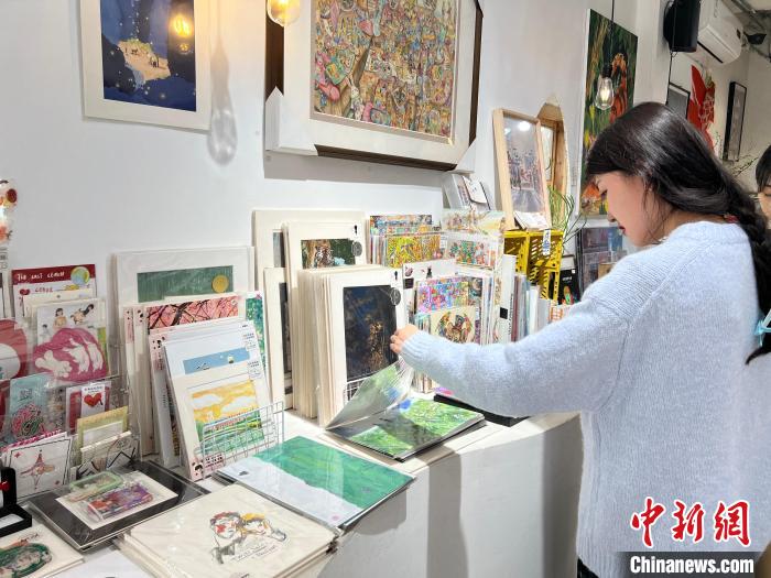 圖為藝術(shù)品商店內(nèi)，顧客挑選插畫作品?！＄婌?攝