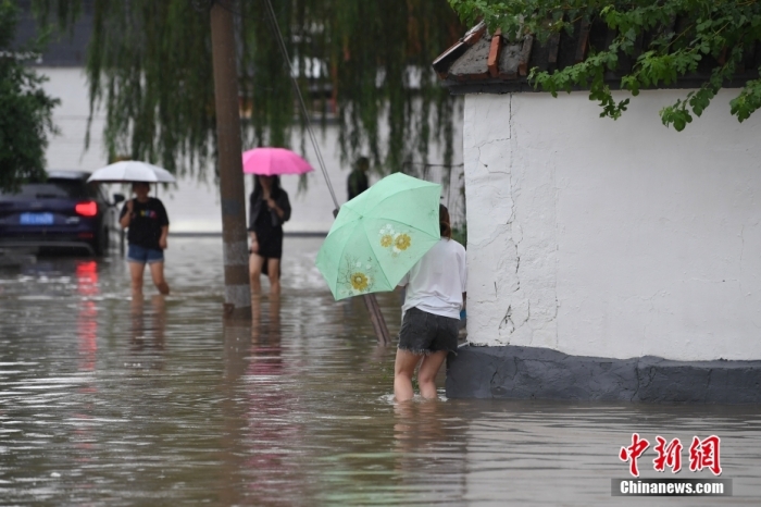 7月31日，市民行走在雨中的北京房山區(qū)瓦窯頭村。北京市氣象臺(tái)當(dāng)日10時(shí)發(fā)布分區(qū)域暴雨紅色預(yù)警信號(hào)。北京市水文總站發(fā)布洪水紅色預(yù)警，預(yù)計(jì)當(dāng)日12時(shí)至14時(shí)，房山區(qū)大石河流域?qū)⒊霈F(xiàn)紅色預(yù)警標(biāo)準(zhǔn)洪水。<a target='_blank' href='/'><p  align=