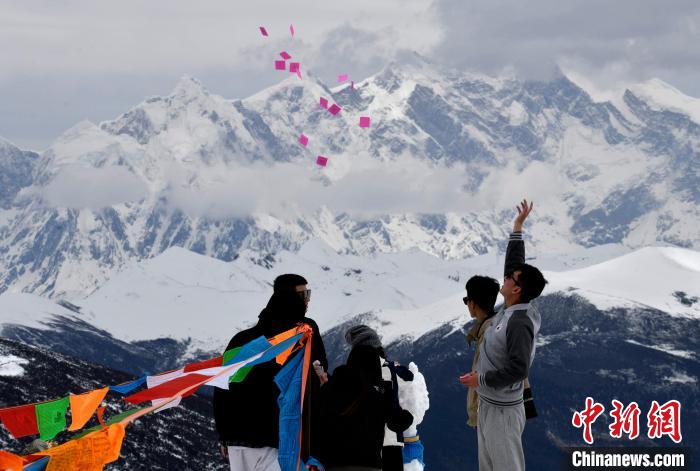 圖為5月14日，游客在西藏林芝色季拉山觀景臺拋灑“隆達”(風馬旗，藏族民眾的一種祈福方式)。　李林 攝